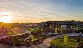 The Boise WaterShed campus at sundown. The foreground shows paved paths and landscaping with the building in the background.