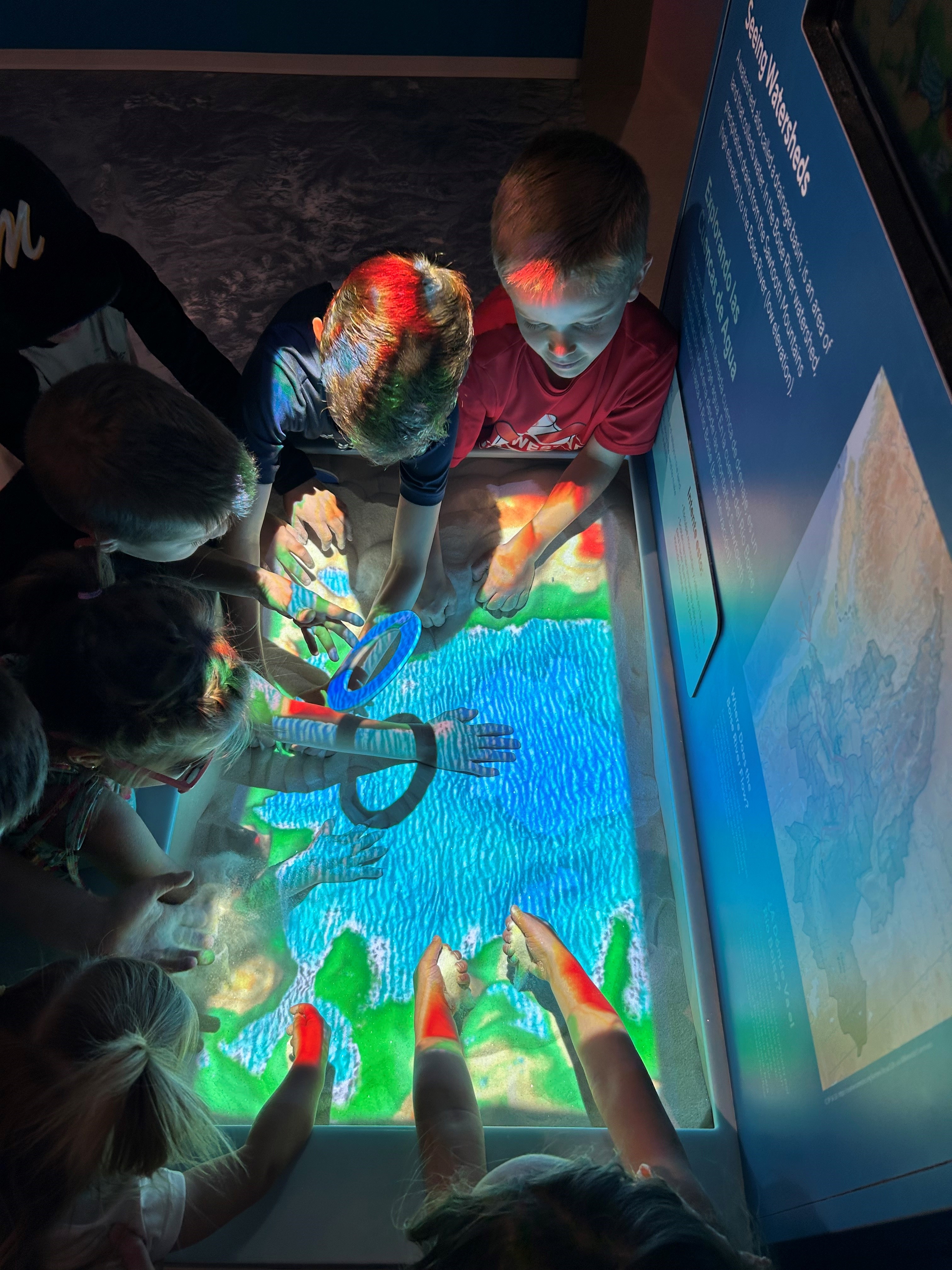 Children playing together with an interactive sand exhibit.