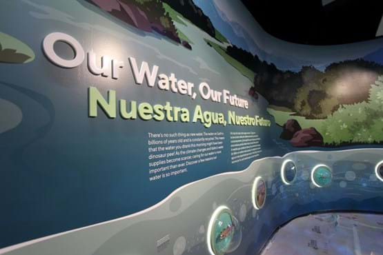 A large wall exhibit says Our Water, Our Future, and translates to Spanish: Nuestra Agua, Nuestra Futuro, with a paragraph below it. The lowest level displays animals that can be found in the Boise River, low enough that small children can examine them through clear domes.