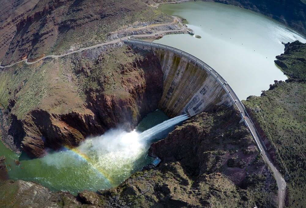 Owyhee Dam letting a controlled flow of water from the reservoir into a river canyon.