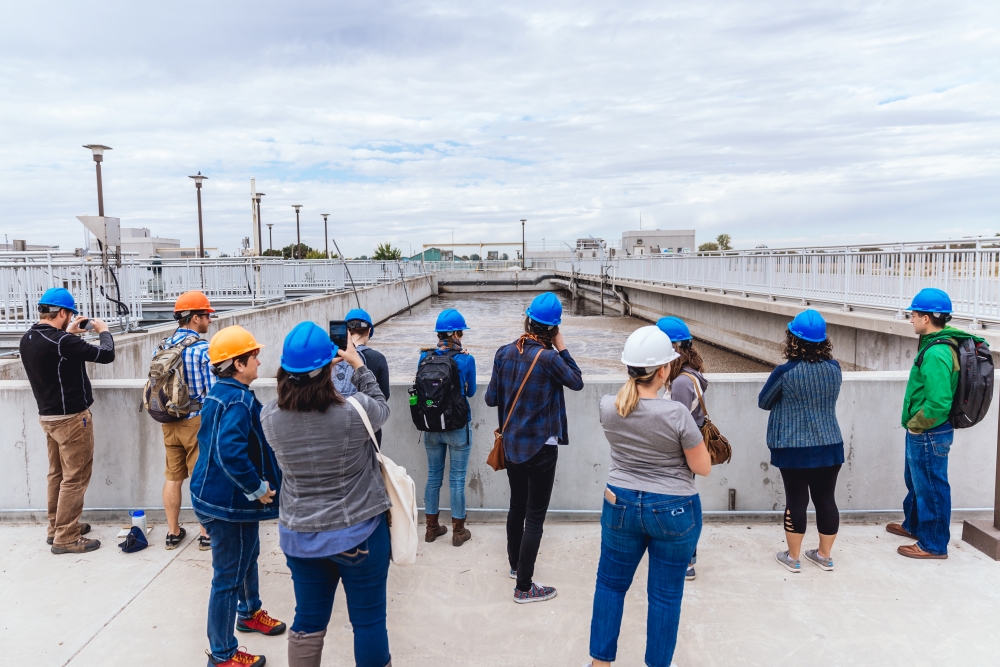 Adult visitors looking over a large outdoor water treatment tank on a guided tour of the Boise WaterShed.